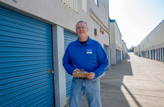 Service representative holding clipboard in front of blue storage containers